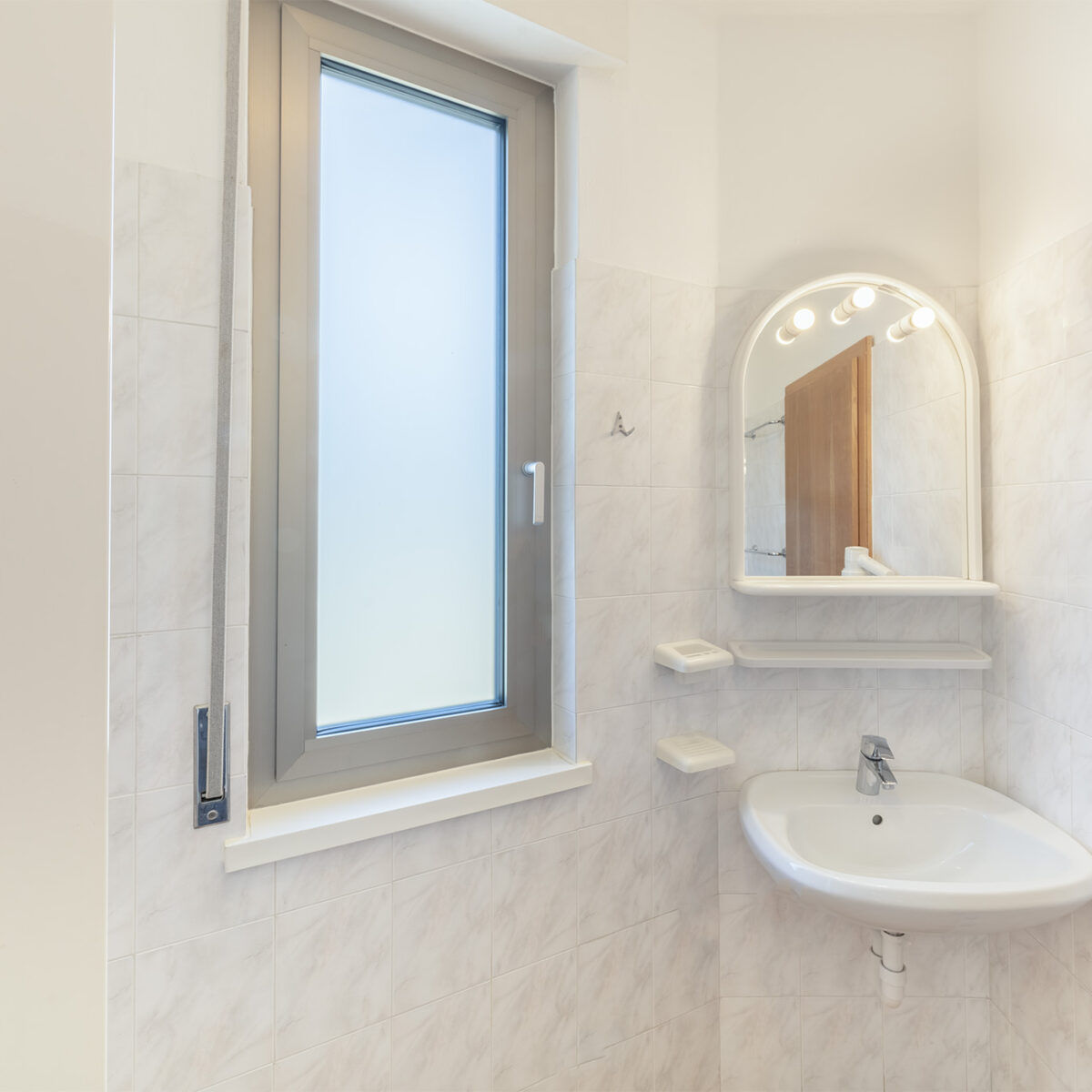 The windowed bathroom is equipped with a shower, toilet, bidet, and a hairdryer.