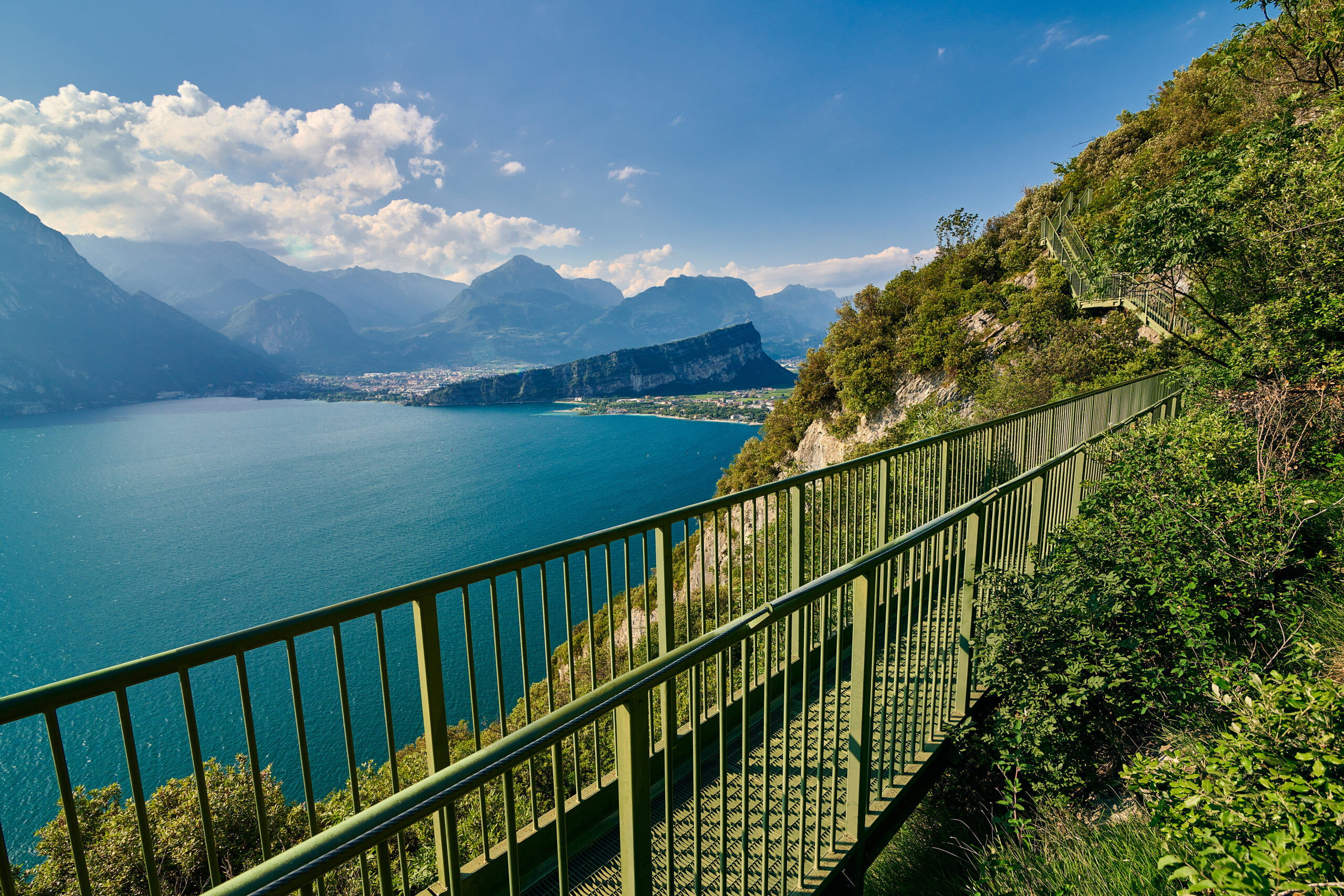 Panoramablick auf den Gardasee vom Busatte-Tempesta-Wanderweg in der Nähe von Nago-Torbole mit der Eisentreppe, umgeben von Bergen in der Sommersaison, Italien
