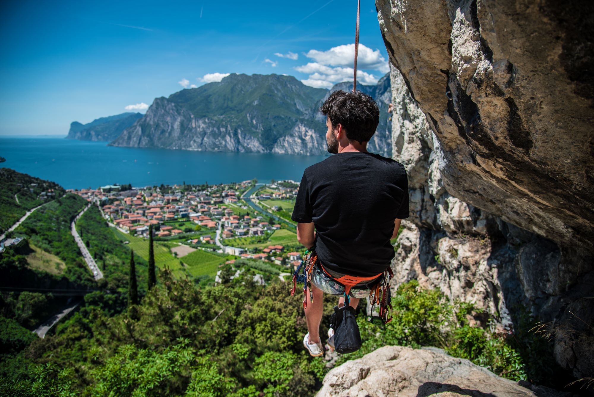 Climber at the summit with a view of Lake Garda